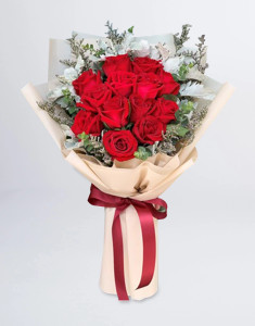 ช่อดอกไม้จัดด้วยดอกกุหลาบสีแดง 14 ดอก แซมใบยูคาลิปตัสและใบหิมะวางอยู่บนโต๊ะ