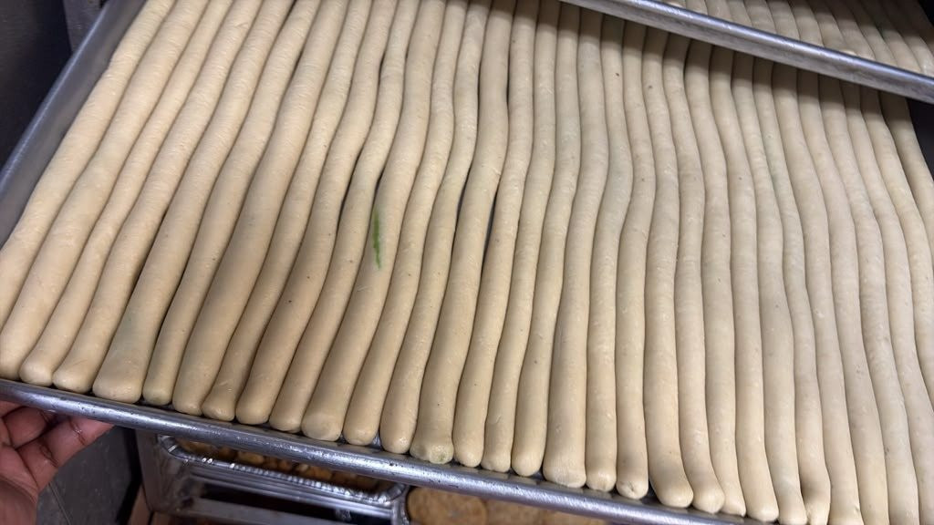 Kaju rolls arranged on baking sheets in the kitchen