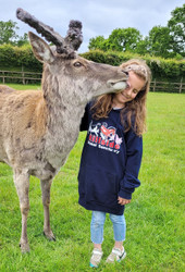 A young supporter modelling a small adult Hoodie while getting a kiss from Bambi, a rescued Red deer at Hillside