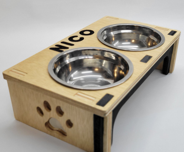 Modern wooden pet bowl stand with two metallic bowls, customizable with engraved text like pet names. Stylish, ergonomic design enhances your pet’s mealtime comfort. Perfect for a cozy and minimalist home decor.