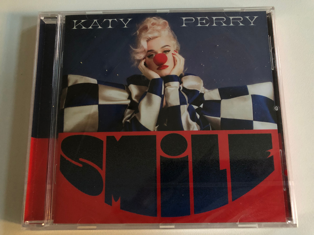 https://cdn10.bigcommerce.com/s-62bdpkt7pb/products/0/images/187325/a_Katy_Perry_Smile_CD_Universal_Music_Group_1__38973.1628768287.1280.1280.JPG?c=2&_gl=1*1uvrjmj*_ga*MTYwNzY1NjY2Mi4xNjI4NzYwNDQ4*_ga_WS2VZYPC6G*MTYyODc2Njk0My4yLjEuMTYyODc2ODAzMS42MA..