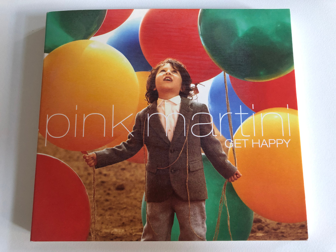 https://cdn10.bigcommerce.com/s-62bdpkt7pb/products/0/images/192587/Pink_Martini_Get_Happy_Nave_Audio_CD_2013_NV828811_1__38434.1632381486.1280.1280.JPG?c=2&_gl=1*zufaz7*_ga*MjA2NTIxMjE2MC4xNTkwNTEyNTMy*_ga_WS2VZYPC6G*MTYzMjM3OTQ5Ni45Ni4xLjE2MzIzODA3MTAuNTc.