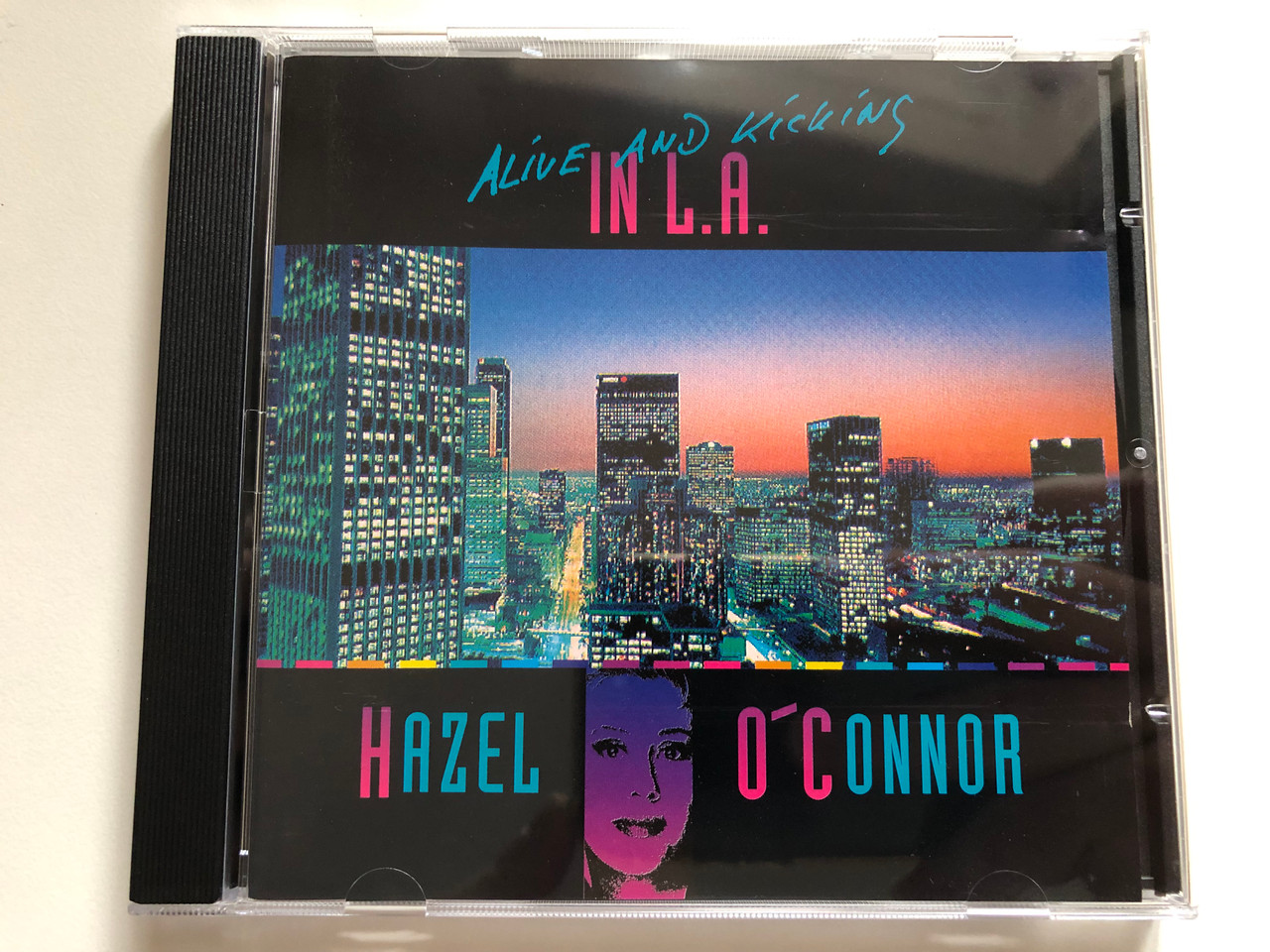 https://cdn10.bigcommerce.com/s-62bdpkt7pb/products/0/images/220095/Alive_And_Kicking_In_LA_-_Hazel_OConnor_Chasha_Records_Audio_CD_1993_L1993-100_1__90135.1648788530.1280.1280.JPG?c=2&_gl=1*1q4sst2*_ga*MjA2NTIxMjE2MC4xNTkwNTEyNTMy*_ga_WS2VZYPC6G*MTY0ODc4MDMyNC4zMzkuMS4xNjQ4Nzg4MzI0LjMx