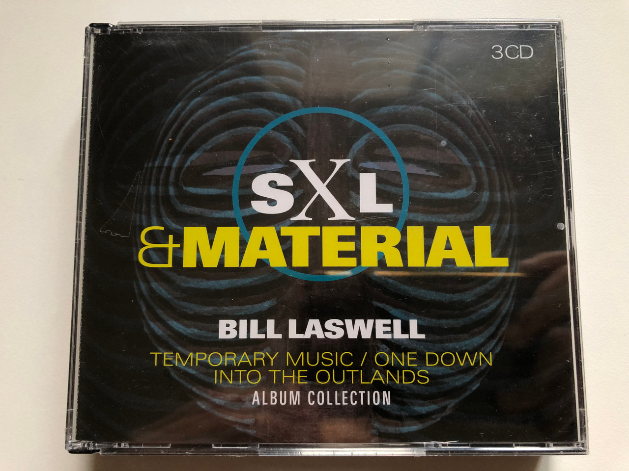 https://cdn10.bigcommerce.com/s-62bdpkt7pb/products/0/images/249228/SXL_Material_-_Bill_Laswell_-_Temporary_Music_One_Down_Into_The_Outlands_Album_Collection_Factory_Of_Sounds_3x_Audio_CD_2018_FOS_2205159_1__38448.1660839513.1280.1280.JPG?c=2&_gl=1*mjowcc*_ga*MjA2NTIxMjE2MC4xNTkwNTEyNTMy*_ga_WS2VZYPC6G*MTY2MDgyNjg1NS41MzEuMS4xNjYwODM5NTA2LjYwLjAuMA..