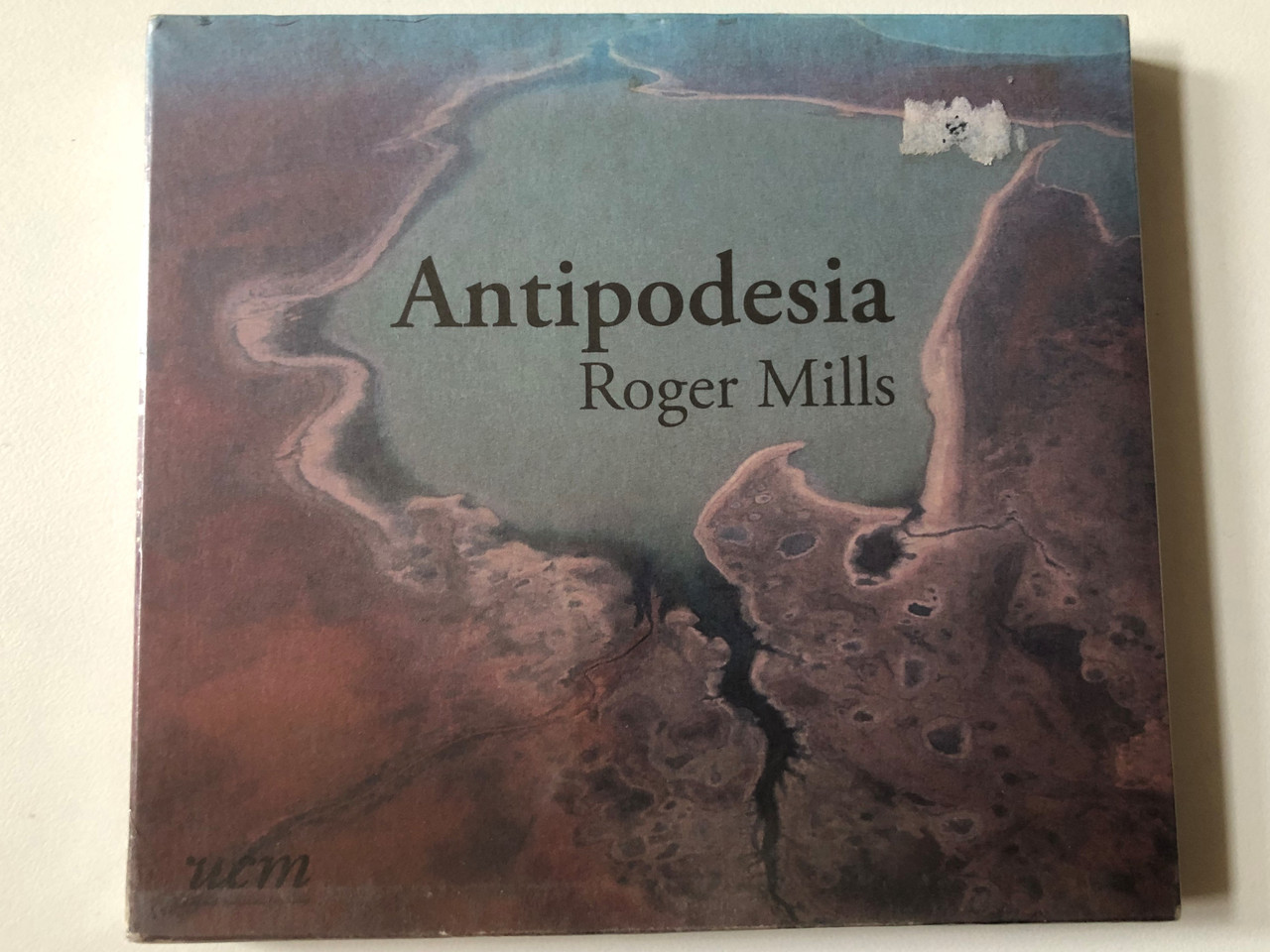 https://cdn10.bigcommerce.com/s-62bdpkt7pb/products/0/images/257055/Roger_Mills_Antipodesia_UnCatalogued_Music_Production_Audio_CD_2007_UCM003_1__43179.1666876421.1280.1280.JPG?c=2&_gl=1*6kd1a0*_ga*MjA2NTIxMjE2MC4xNTkwNTEyNTMy*_ga_WS2VZYPC6G*MTY2Njg3MzQxMS42MDUuMS4xNjY2ODc2MjU5LjMzLjAuMA..