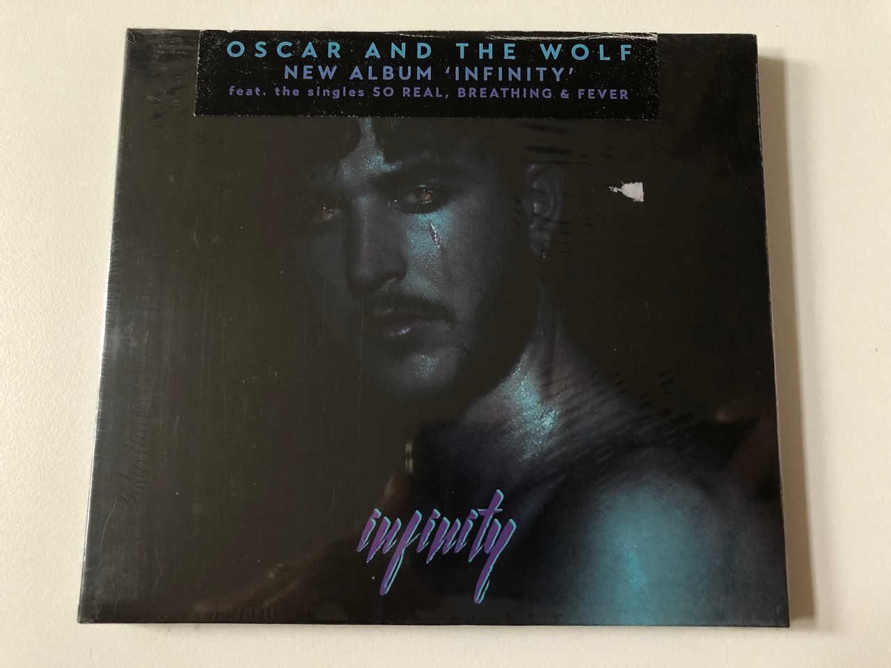 https://cdn10.bigcommerce.com/s-62bdpkt7pb/products/0/images/257172/Oscar_And_The_Wolf_New_Album_Infinity_Feat._The_Singles_So_Real_Breathing_Fever_Debonair_Audio_CD_2017_PIASR985CDX_1__73618.1666969085.1280.1280.JPG?c=2&_gl=1*1a2qufq*_ga*MjA2NTIxMjE2MC4xNTkwNTEyNTMy*_ga_WS2VZYPC6G*MTY2Njk2MjE1OC42MDcuMS4xNjY2OTY4OTI2LjE4LjAuMA..
