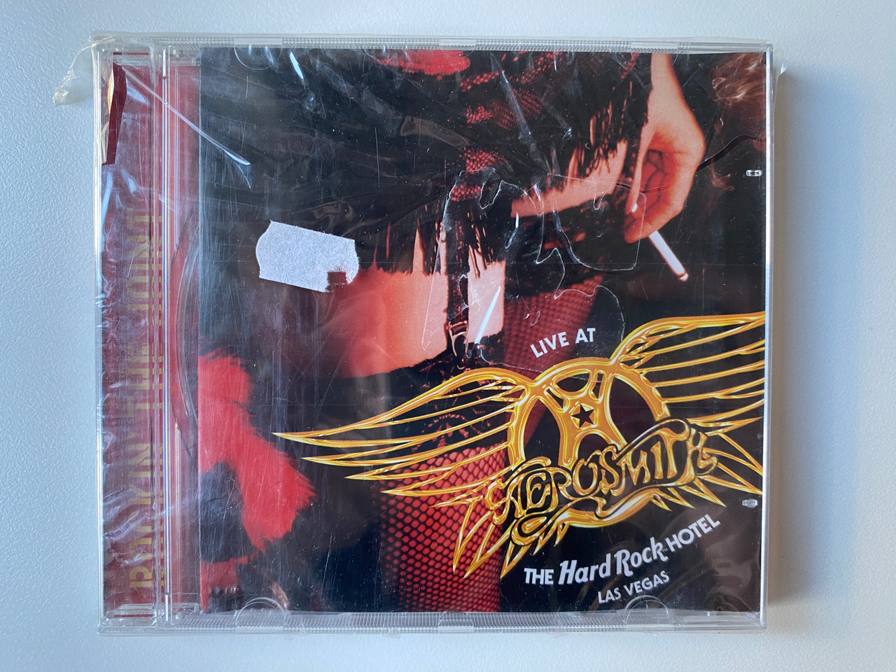 https://cdn10.bigcommerce.com/s-62bdpkt7pb/products/0/images/302060/Aerosmith_Rockin_The_Joint_Live_At_The_Hard_Rock_Hotel_Las_Vegas_Columbia_Audio_CD_2005_82876724212_1__65667.1695970306.1280.1280.jpg?c=2&_gl=1*eq1sdk*_ga*MjA2NTIxMjE2MC4xNTkwNTEyNTMy*_ga_WS2VZYPC6G*MTY5NTk2Nzc2My4xMDc2LjEuMTY5NTk3MDE2My41MS4wLjA.