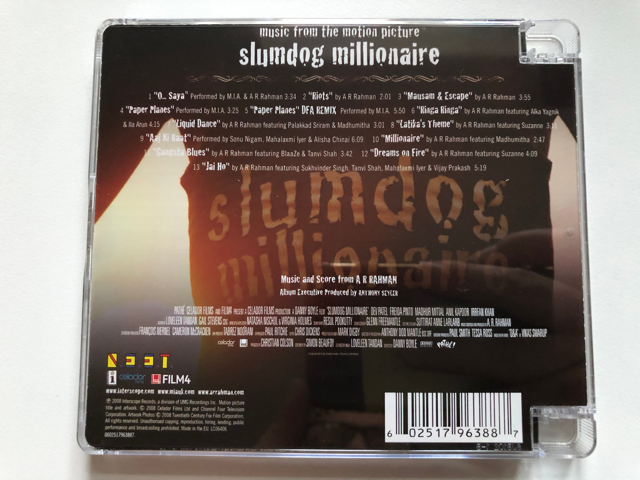 https://cdn10.bigcommerce.com/s-62bdpkt7pb/products/43702/images/237102/Slumdog_Millionaire_Music_From_The_Motion_Picture_-_Featuring_Music_And_Score_From_A_R_Rahman_Interscope_Records_Audio_CD_2008_0602517963887_2__48629.1657046045.1280.1280.JPG?c=2&_gl=1*1l5zmud*_ga*MjAyOTE0ODY1OS4xNTkyNDY2ODc5*_ga_WS2VZYPC6G*MTY1Nzc5MjM3NS4xODMwLjEuMTY1NzgwMjA4Mi42MA..