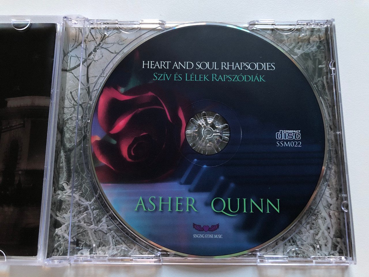 https://cdn10.bigcommerce.com/s-62bdpkt7pb/products/49449/images/252696/Asher_Quinn_-_Heart_And_Soul_Rhapsodies_improvised_piano_pieces_Sziv_Es_Lelek_Rapszodiak_-_zongoraimprovizaciok_Singing_Stone_Music_Audio_CD_SSM022_3__31074.1661790414.1280.1280.JPG?c=2&_gl=1*1j5nryd*_ga*MjA2NTIxMjE2MC4xNTkwNTEyNTMy*_ga_WS2VZYPC6G*MTY2MTc4MjI5Ny41NDEuMS4xNjYxNzkwMzYwLjU0LjAuMA..