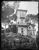 Warringah Lodge, Cremorne, looking up with Macpherson family members seated on rock ledge and standing on upstairs balcony.