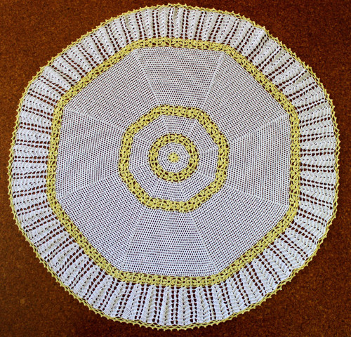 Octagonal crocheted baby shawl featuring rings of daisy chains.