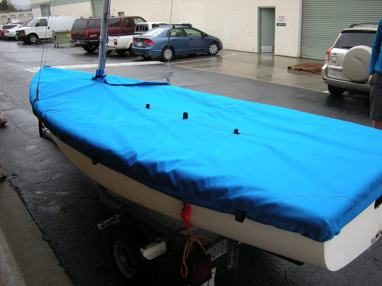 Flying Junior Mast Up Flat Mooring Cover by SLO Sail and Canvas. Reinforcements positioned over blocks and cleats prevent chafing. Webbing loops are sewn around the perimeter of our top covers allowing your cover to be tied to your boat. 
