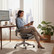 Person sitting comfortably in a Healthy Posture Hinomi X2 Pro ergonomic office chair at a home office desk, demonstrating posture support and modern design.