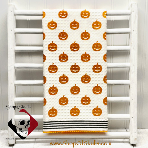 Pumpkin print kitchen towel with woven and pompom trim.