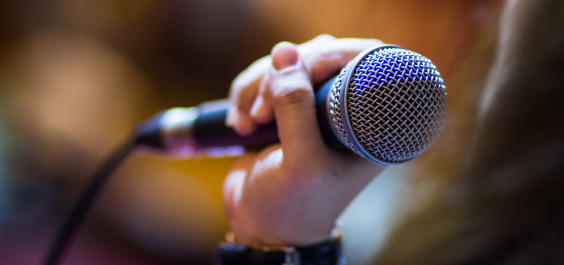 Young woman nervously grasps a microphone, about to speak or sing in public