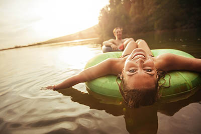 Young man and woman smile as they float down the river