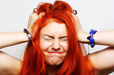 Stressed red-headed woman puts her hands to her head in frustration or worry