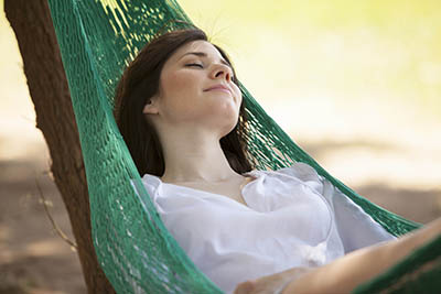 Young woman relaxes peacefully in a hammock on the beach