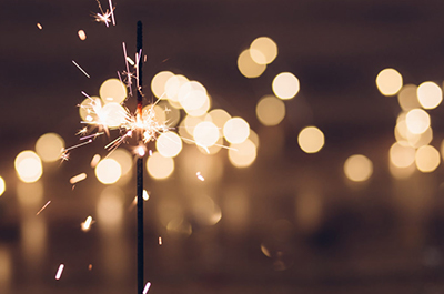 A sparkler burning with light from others visible behind it