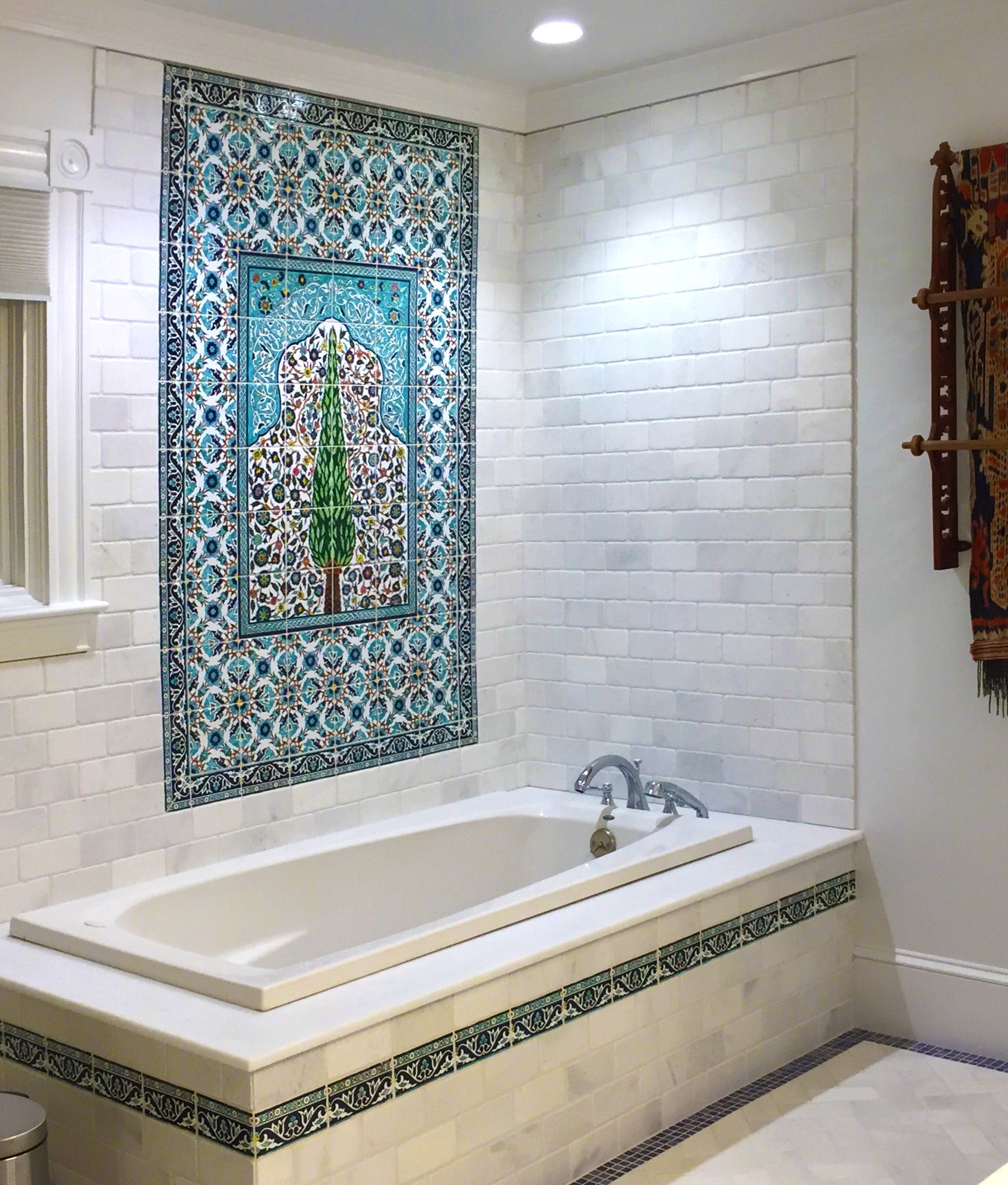 hand painted ceramic tile mural from Mexico decorating bathroom wall above a bathtub