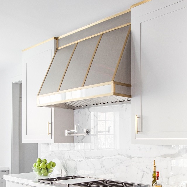 metal kitchen range hood made of zinc decorated with a brass trim and straps