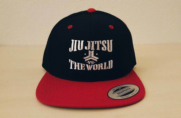 OGA Open Guard Apparel Jiu Jitsu vs The World Snapback hat.  Red black hat with white embroidery in the background of his picture..  Jiu Jitsu vs the world series from Open guard apparel. 

Enjoy Free Shipping on all products storewide today. 