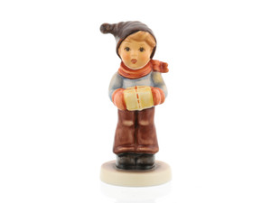 M.I. Hummel 'For Me?' figurine (HUM 2067/B) showing a boy in a red scarf holding a gold gift box. A close-up of the gold-wrapped package and the red twine detail