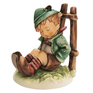 M.I. Hummel 'Afternoon Nap' figurine HUM 836 showing a young hiker boy asleep on the grass with his walking stick.
