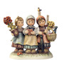 M.I. Hummel Limited Edition figurine HUM 605 Joyful Gifts featuring three young girls carrying flowers, wine, and a gingerbread heart, handcrafted in Germany.