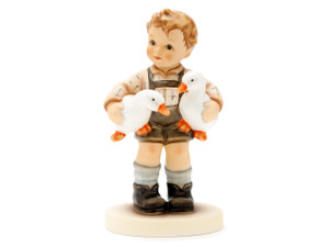 M.I. Hummel figurine HUM 2394 Birds of a Feather featuring a boy in traditional Bavarian Lederhosen holding two glossy white ducklings, handcrafted in Germany.
