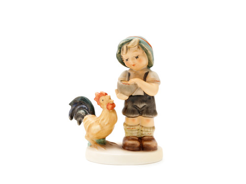 M.I. Hummel figurine HUM 2227 Morning Call featuring a young boy kneeling to feed a colorful rooster, handcrafted in Germany.
