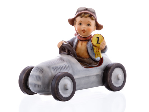 M.I. Hummel figurine HUM 2420 Winner featuring a boy in a silver racing soapbox car holding a first-place trophy, handcrafted in Germany.