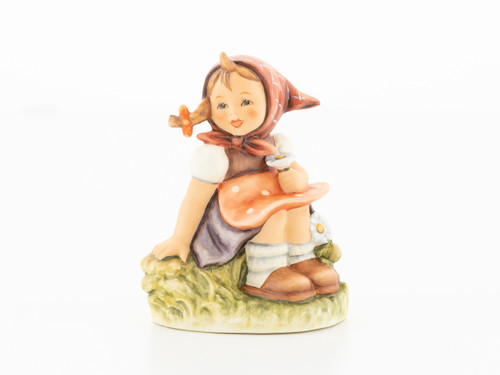 M.I. Hummel figurine HUM 459 of a girl sitting in a meadow picking flowers.