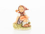 M.I. Hummel figurine HUM 459 of a girl sitting in a meadow picking flowers.