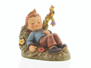 M.I. Hummel figurine HUM 550 Summerdream featuring a young boy sleeping peacefully in a meadow with a small bird nearby, handcrafted in Germany.