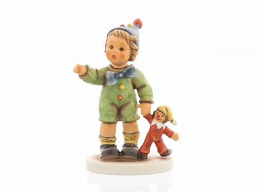 M.I. Hummel figurine HUM 2428 Carnival Can Come, featuring a girl in a green costume with a pom-pom hat holding a toy clown, handcrafted in Germany.