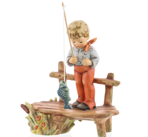 M.I. Hummel 'The Angler' (HUM 566) showing a boy on a bench pulling a large fish with a fishing rod. A close-up of the large hand-painted fish and the tension in the boy's fishing line.