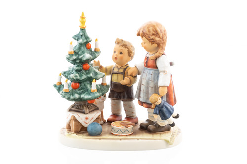 M.I. Hummel figurine HUM 2442 "Under the Christmas Tree" featuring a brother and sister with a doll and a cat by a decorated Christmas tree.