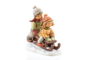 Winter Days HUM 2072 M.I. HUMMEL figurine featuring a brother and sister sledding. Close-up of the hand-painted details and rosy cheeks on the HUM 2072 Winter Days figurine.