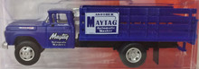 Dark blue stake truck. 1960's cab with white Maytag graphics on the door.  There is also a Maytag advertising sign on the side of the stake bed.