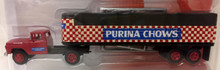 Red 1960's Ford Tractor with blue and white graphics on the door. Trailer is the classic red and white checkerboard with black cover.  'Purina Chow'  in white letters on a blue background is on the side of the trailer. 'Ralston Purina Company' is also printed along the front of the trailer.