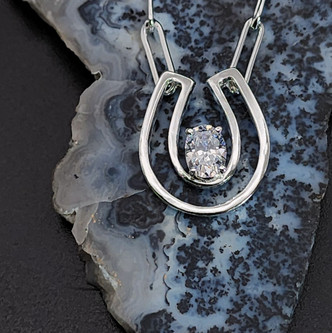 Sterling silver open concept horseshoe with CZ.This necklace is made in sterling silver or can be in gold. Price depends on type of metal and gemstone choose. This necklace is pictured with a sapphire or a cubic zirconium. This necklace can be done in 14K gold and paved in diamonds with any chain. We are featuring a paper clip chain . Call to create your custom piece.8593330458.