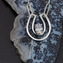 Sterling silver open concept horseshoe with CZ.This necklace is made in sterling silver or can be in gold. Price depends on type of metal and gemstone choose. This necklace is pictured with a sapphire or a cubic zirconium. This necklace can be done in 14K gold and paved in diamonds with any chain. We are featuring a paper clip chain . Call to create your custom piece.8593330458.