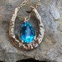14k gold hammered horseshoe pendant. The shoe is elongated and reflects light playing on the piece. Gemstones are separate as are the chains. We can use your gemstone or one of ours. Pictured with topaz and green tourmaline. Call 8593330458 to order gemstones or chains. Gemstones and chains sold separately