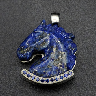 A Lapis carved horse head pendant that is paved with lab sapphires in the lower border to emphasis the blue in the stone. It is a very elegant piece set into geometric patterned sterling silver. This is a truly a very elegant piece with iron pyrite shimmering into the lapis.