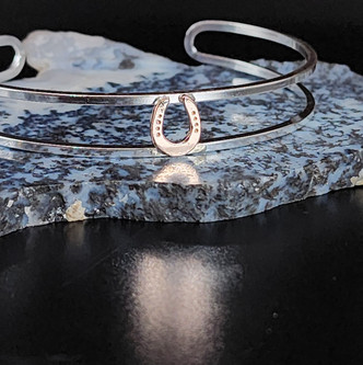 A dainty sterling silver bracelet featuring a small 14k gold horseshoe. A fun play between silver and gold.