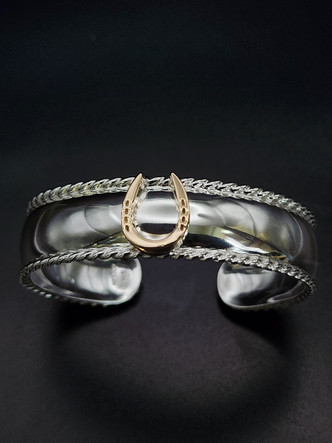 A 14k gold horseshoe soldiered on a sterling silver cuff bracelet. The cuff features a roping detail on the edge. Can be customized. 8593330458