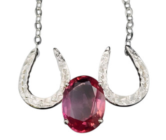 A pink sapphire nestled between 2 sterling silver horseshoes featured in a necklace. Chain is 18 inches. If you wish to make length different call 8593330458