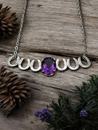 A sterling silver bar horse shoe necklace with a 8x10 AAA amethyst. The stone is nestled in the middle of the horse shoes and balances the shoes. The chain is sterling silver and 18 inches long.