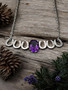 A sterling silver bar horse shoe necklace with a 8x10 AAA amethyst. The stone is nestled in the middle of the horse shoes and balances the shoes. The chain is sterling silver and 18 inches long.